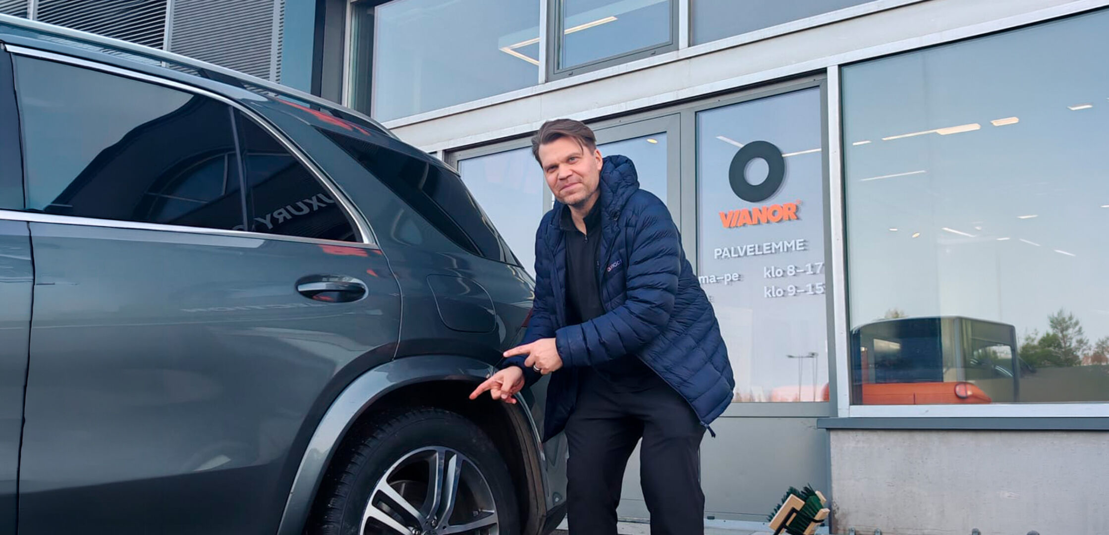 Henkilö osoittaa autonrengasta Vianorin palvepisteen ulkopuolella ja ikkunassa näkyy opasteita.
