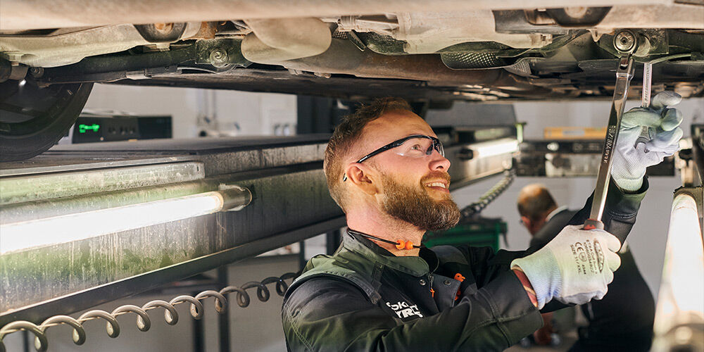 Mekaniker under bilen som utfører bilservice