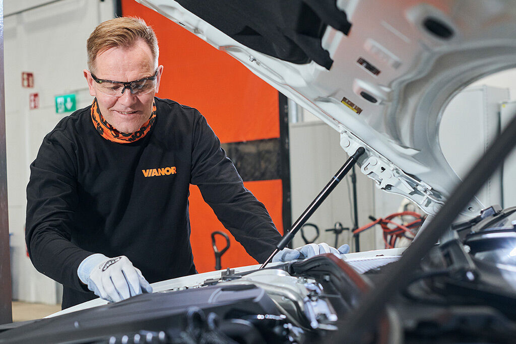 Vianor-mekaniker sjekker bilbatteriet med bilens panser åpent