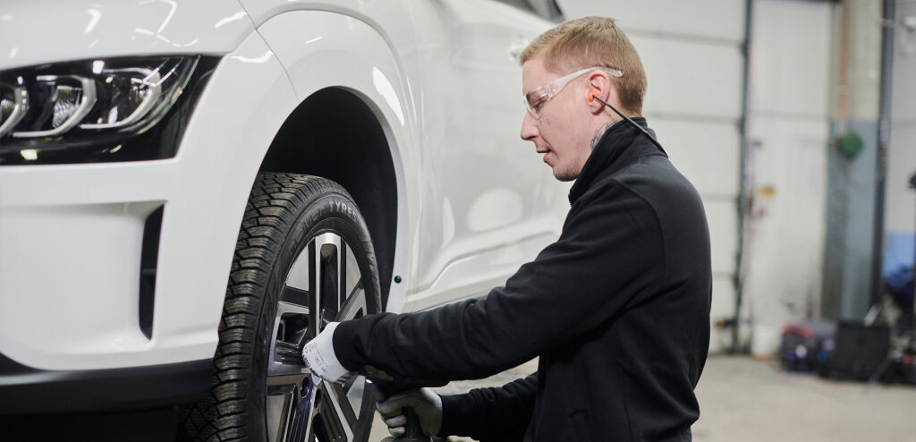 Vianors expert kontrollerar slitaget på elbilens däck vid service.