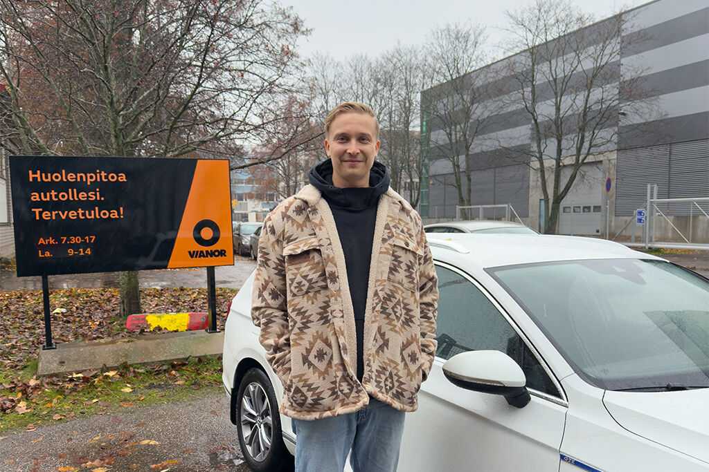 Mies seisomassa ulkona valkoisen auton edessä