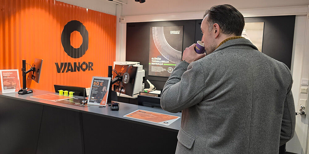 Person standing in front of Vianor service centers customer counter sipping coffee