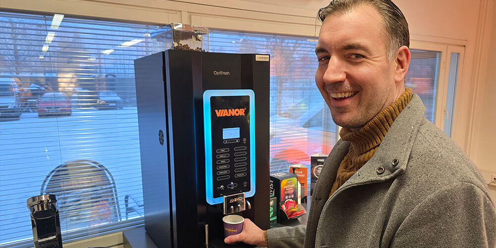 Person smiling in front of coffee automat inside Vianor service center