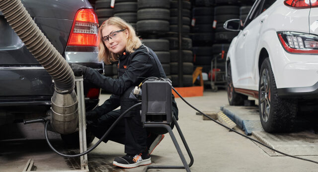 Jente med måleinstrument foran bil