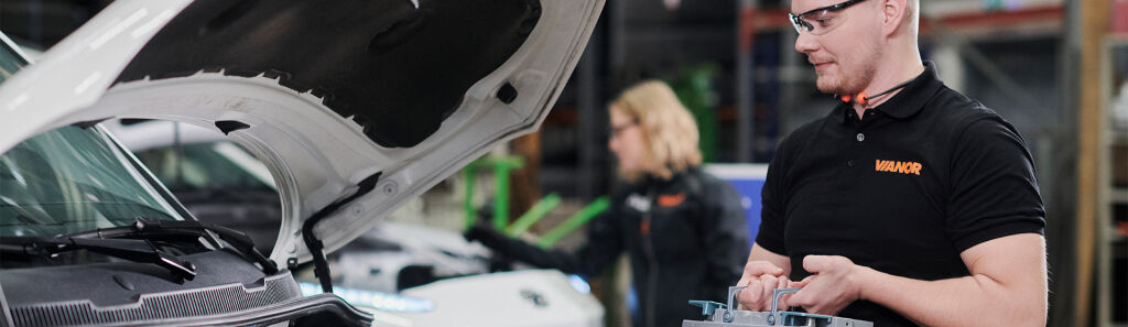 Vianor-mekaniker sjekker bilbatteriet med bilens panser åpent